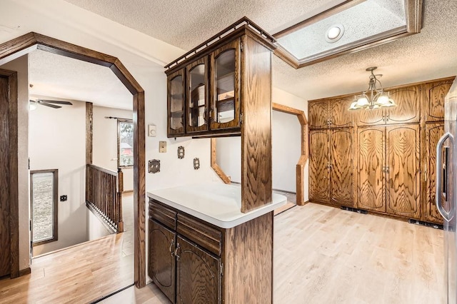 kitchen featuring hanging light fixtures, dark brown cabinets, a textured ceiling, and light hardwood / wood-style floors