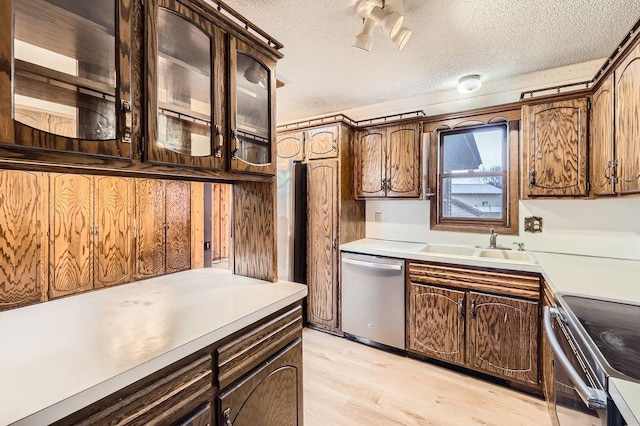 kitchen with stainless steel appliances, sink, light hardwood / wood-style floors, and a textured ceiling