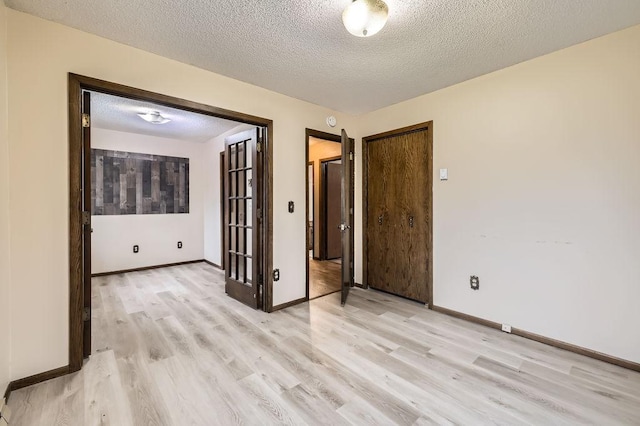 spare room featuring light hardwood / wood-style floors and a textured ceiling