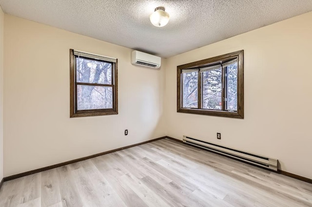 empty room featuring a baseboard radiator, a textured ceiling, a wall unit AC, and light hardwood / wood-style floors