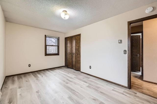 unfurnished room with light hardwood / wood-style flooring and a textured ceiling