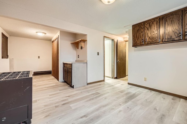 kitchen featuring dark brown cabinets, a textured ceiling, and light hardwood / wood-style floors