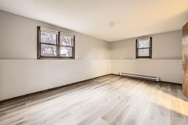 spare room with light hardwood / wood-style flooring, a baseboard radiator, and a textured ceiling