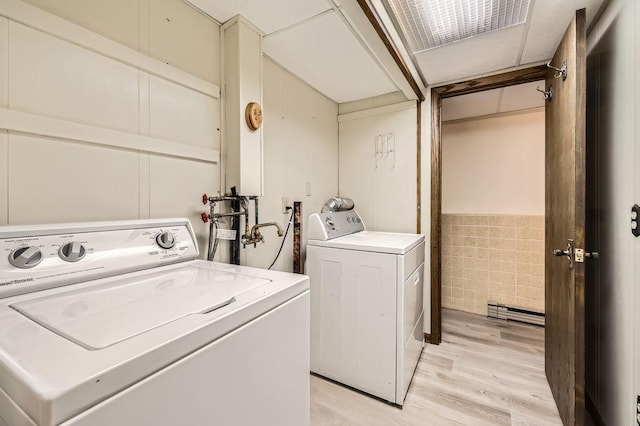 laundry room featuring light wood-type flooring, tile walls, and independent washer and dryer