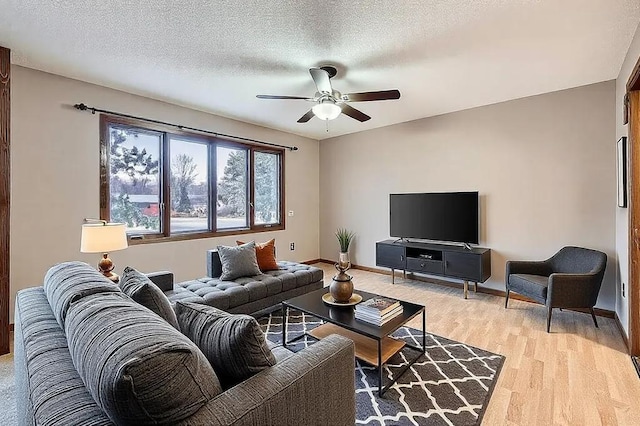 living room with ceiling fan, light hardwood / wood-style flooring, and a textured ceiling