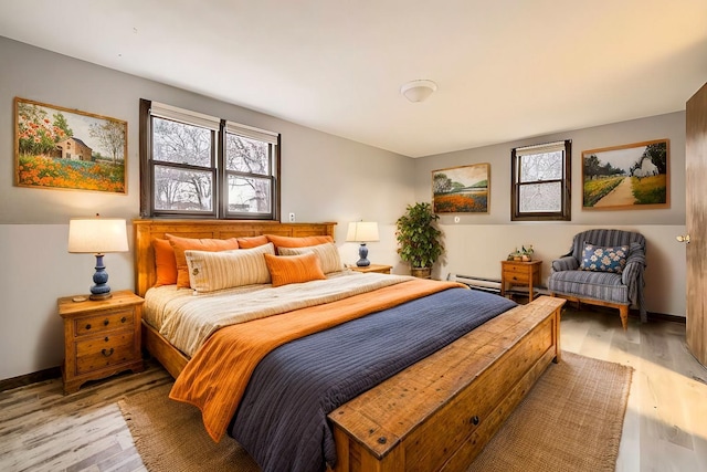 bedroom with light hardwood / wood-style flooring, multiple windows, and a baseboard radiator