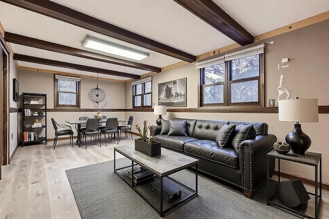 living room with a wealth of natural light, beam ceiling, and light hardwood / wood-style flooring