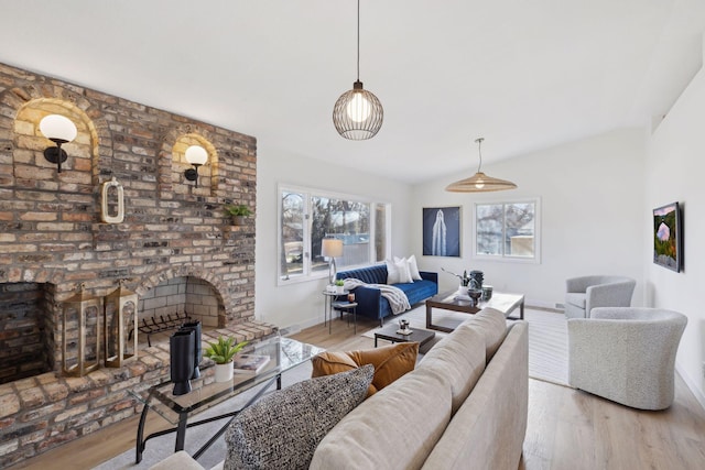 living room with lofted ceiling, light hardwood / wood-style floors, and a brick fireplace