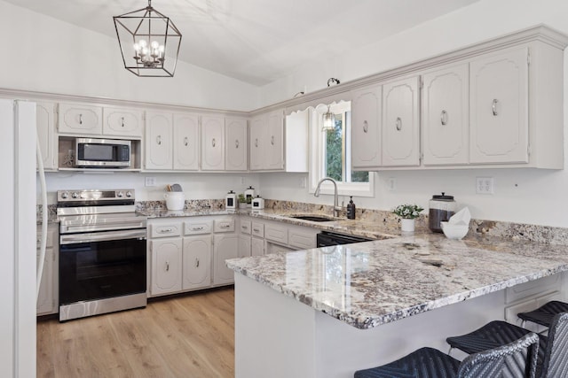 kitchen with stainless steel appliances, sink, kitchen peninsula, and decorative light fixtures