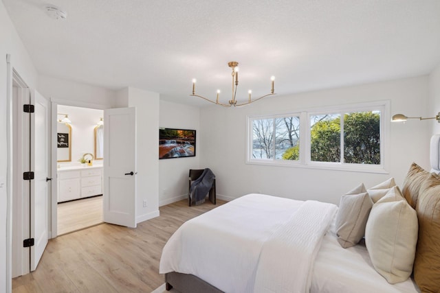 bedroom with connected bathroom, a notable chandelier, and light wood-type flooring