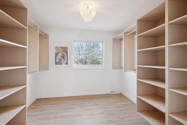 walk in closet featuring hardwood / wood-style flooring and an inviting chandelier