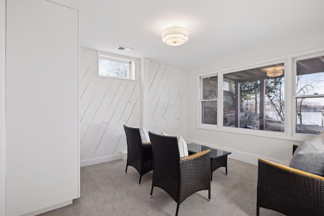 carpeted dining area featuring wooden walls