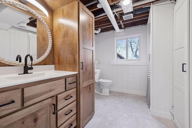 bathroom with wooden walls, vanity, and toilet