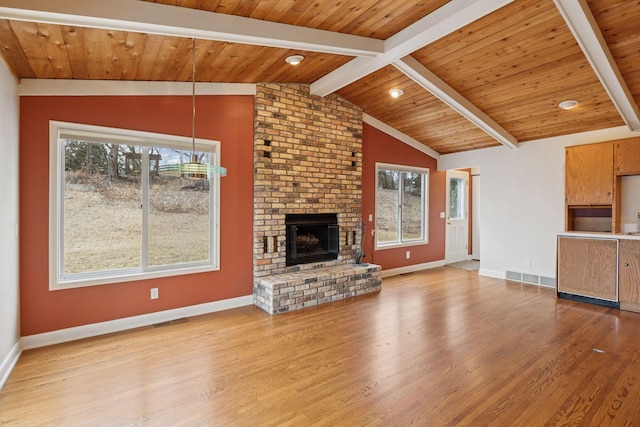 unfurnished living room with lofted ceiling with beams, a healthy amount of sunlight, a fireplace, and wood finished floors