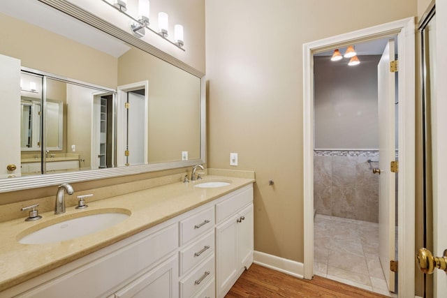 full bathroom featuring a sink, a tile shower, and double vanity