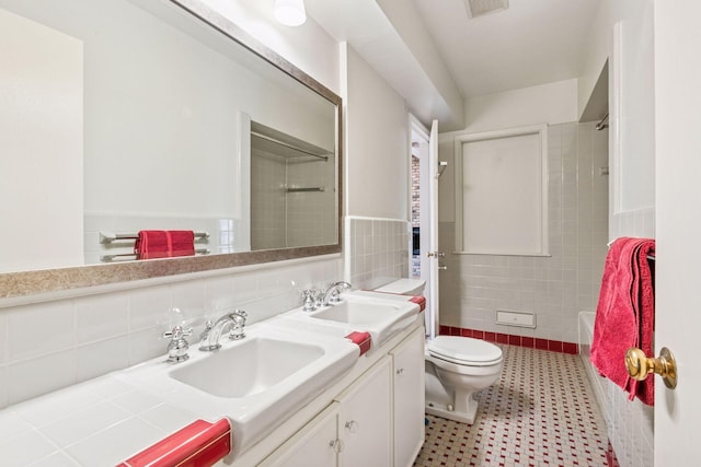 bathroom featuring a sink, tile walls, toilet, and double vanity