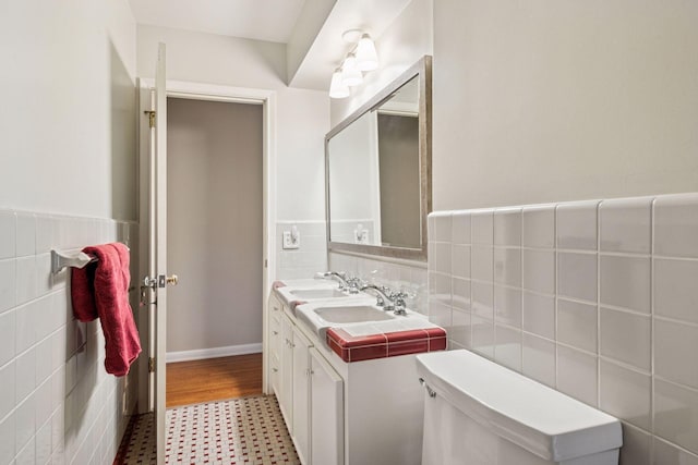 bathroom featuring toilet, a wainscoted wall, vanity, tile walls, and tile patterned floors