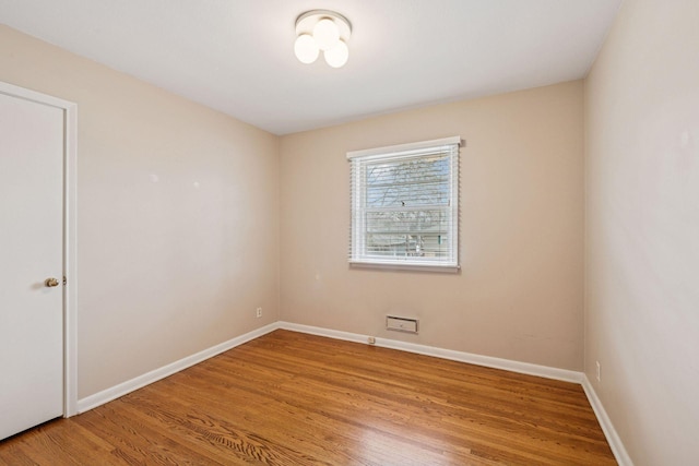 spare room with baseboards and wood finished floors