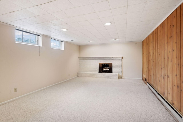 basement featuring wooden walls, a fireplace, baseboards, baseboard heating, and carpet