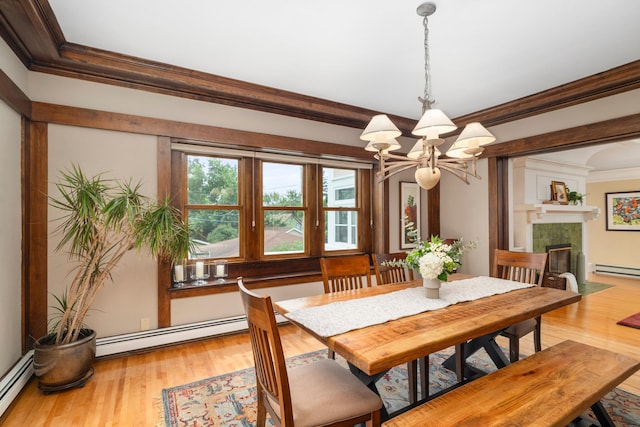 2328 3rd St, Duluth, MN 55812 - dining room featuring crown molding, a chandelier, baseboard heating, a tiled fireplace, and wood finished floors