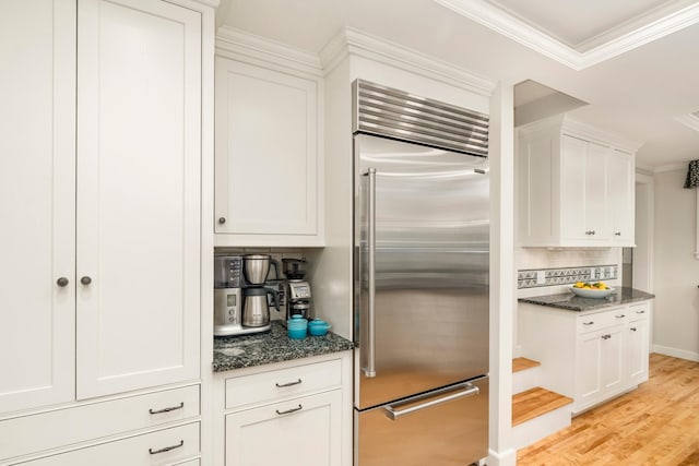 2328 3rd St, Duluth, MN 55812 - kitchen featuring built in fridge, dark stone counters, decorative backsplash, white cabinetry, and crown molding