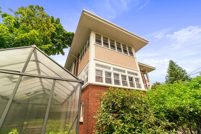 2328 3rd St, Duluth, MN 55812 - back of house with stucco siding, brick siding, and a greenhouse