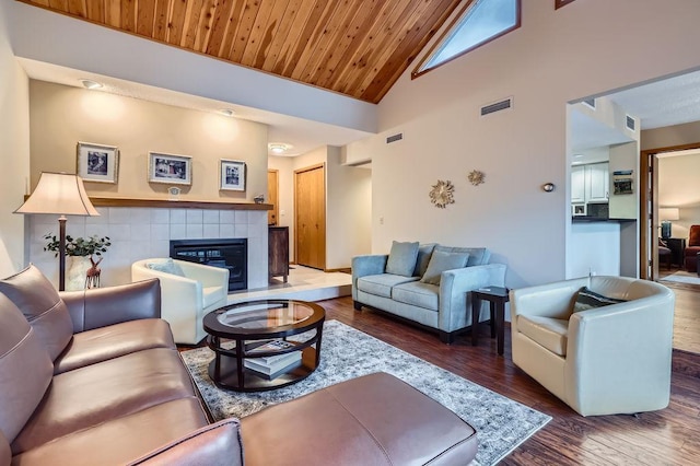 living area featuring a tile fireplace, wooden ceiling, visible vents, and wood finished floors