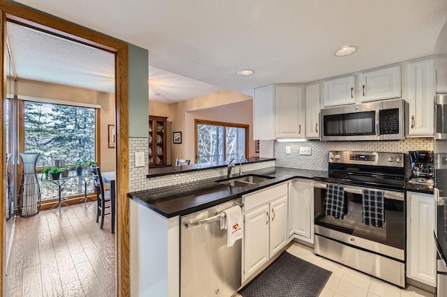 kitchen featuring appliances with stainless steel finishes, white cabinets, a sink, and backsplash