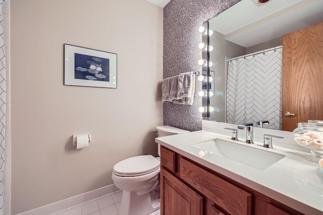 bathroom featuring curtained shower, toilet, vanity, baseboards, and tile patterned floors