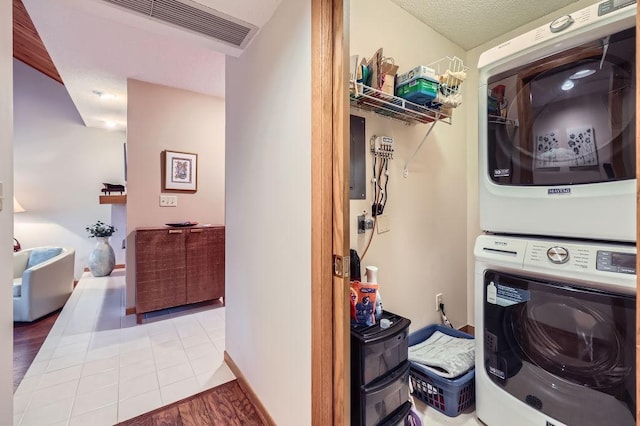 clothes washing area with visible vents, laundry area, stacked washer and clothes dryer, and tile patterned floors