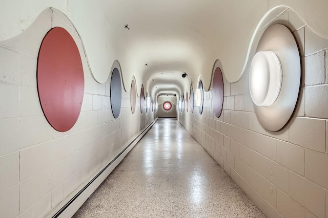 corridor featuring concrete block wall and speckled floor