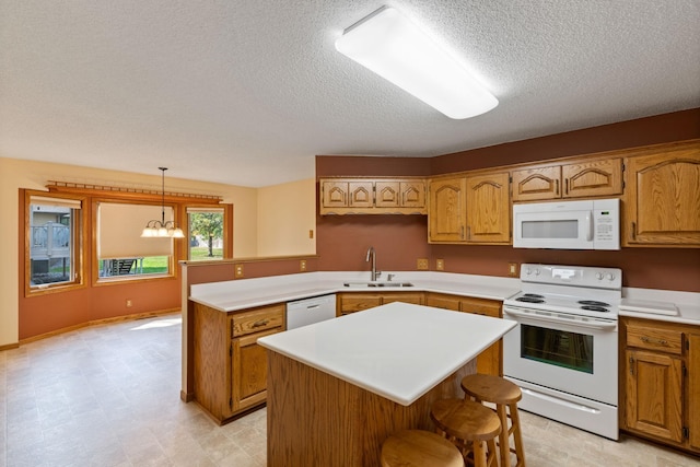 kitchen with pendant lighting, white appliances, sink, a kitchen island, and a chandelier