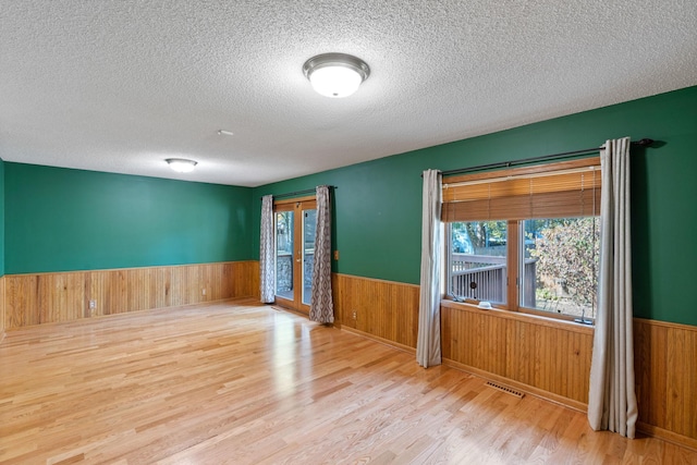 unfurnished room with hardwood / wood-style floors, a textured ceiling, and wood walls