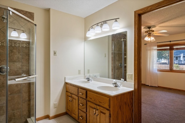 bathroom featuring vanity, ceiling fan, a shower with door, and a textured ceiling