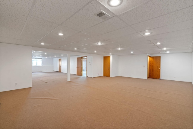 basement with a paneled ceiling and light carpet