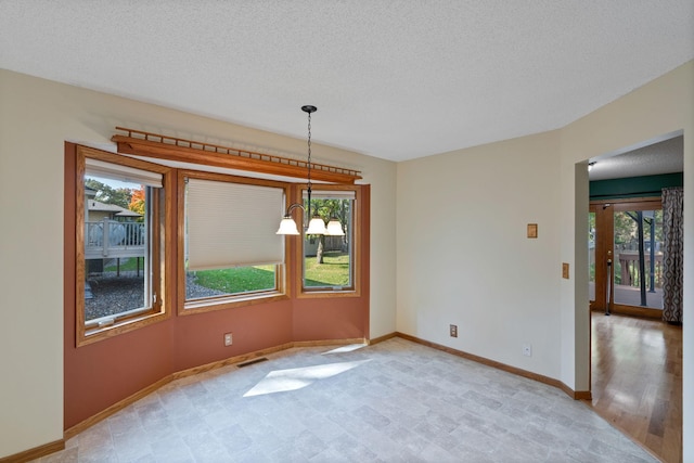 unfurnished dining area with light wood-type flooring, a textured ceiling, and an inviting chandelier