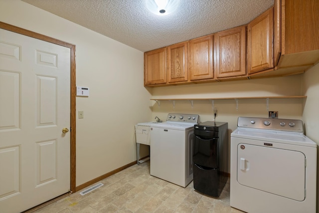 laundry room featuring cabinets, a textured ceiling, and washer and clothes dryer