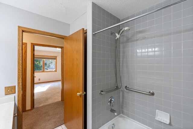 bathroom featuring vanity, a textured ceiling, and tiled shower / bath