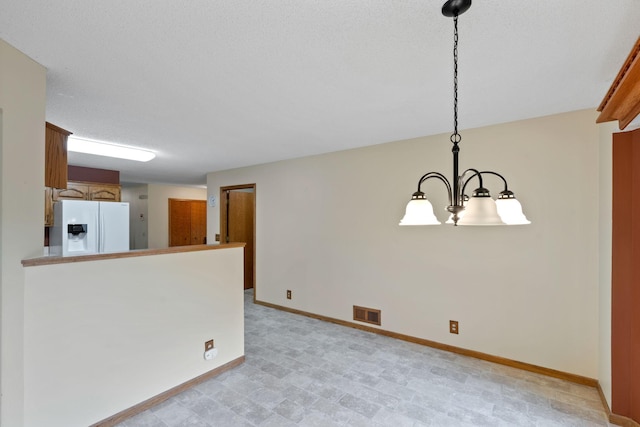 unfurnished room featuring a textured ceiling and an inviting chandelier