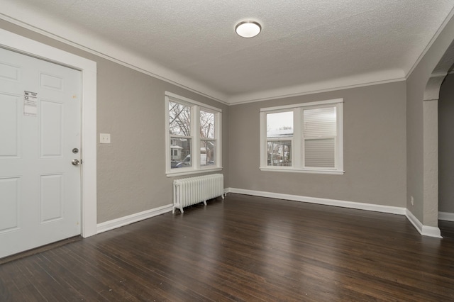 entrance foyer with dark hardwood / wood-style flooring, ornamental molding, a textured ceiling, and radiator