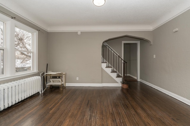 spare room with dark hardwood / wood-style flooring, crown molding, radiator heating unit, and a textured ceiling