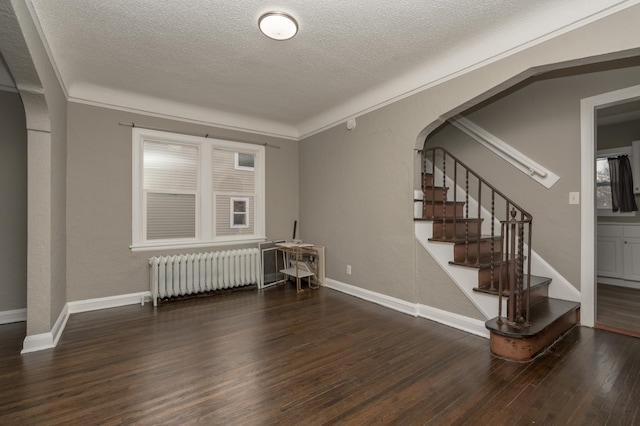 interior space featuring dark hardwood / wood-style floors, ornamental molding, a textured ceiling, and radiator