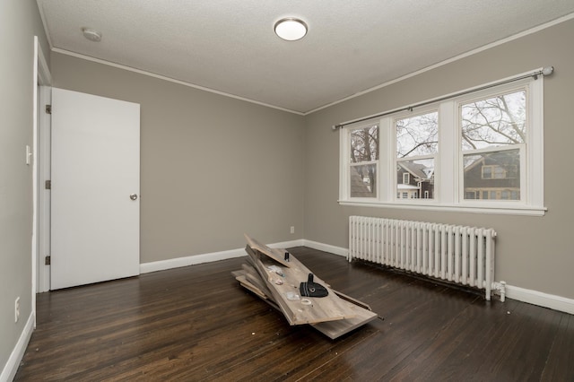 spare room featuring crown molding, dark hardwood / wood-style flooring, radiator heating unit, and a textured ceiling