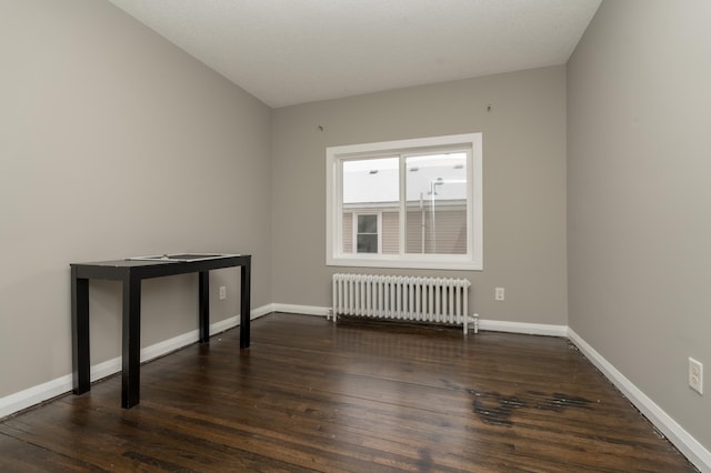 spare room with radiator heating unit, a textured ceiling, and dark hardwood / wood-style floors