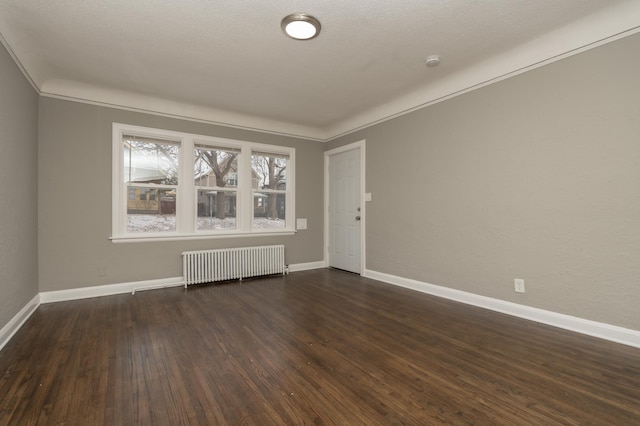 spare room with a textured ceiling, dark hardwood / wood-style floors, radiator, and crown molding