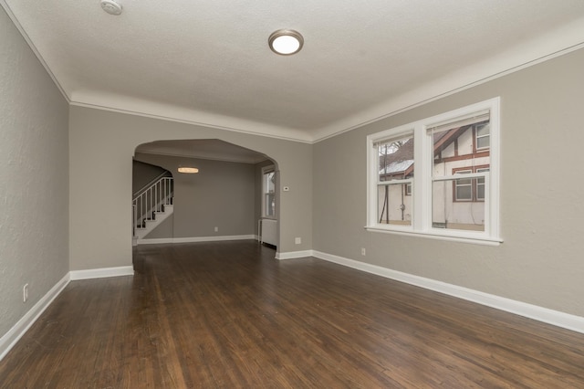 empty room with a textured ceiling, dark hardwood / wood-style flooring, and ornamental molding