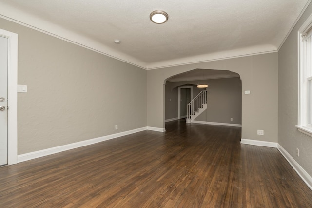 empty room with dark hardwood / wood-style flooring, ornamental molding, and a textured ceiling