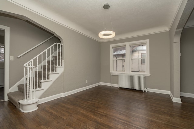 unfurnished dining area with dark hardwood / wood-style flooring, radiator heating unit, a textured ceiling, and ornamental molding