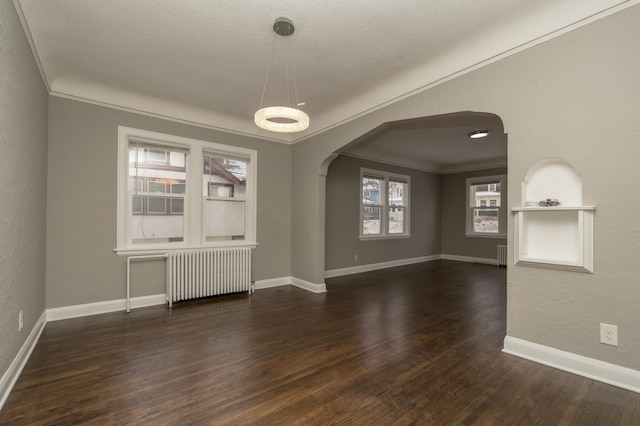 spare room with a textured ceiling, radiator heating unit, dark hardwood / wood-style floors, and ornamental molding