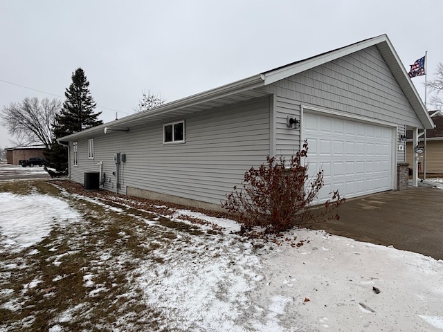 view of snow covered exterior featuring an outbuilding and a garage